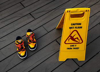 Pair of shoes next to a wet foor sign on the ground